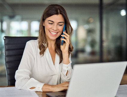 Woman smiling while talking on phone in office