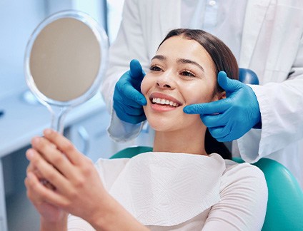 Woman smiling while looking at reflection in handheld mirror