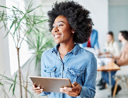 Woman smiling while holding tablet in office