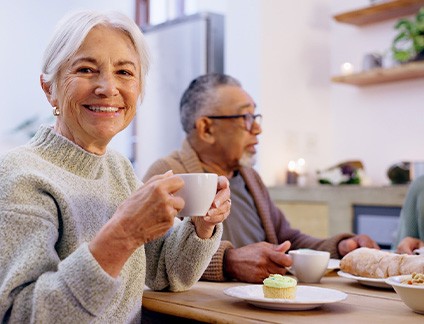 Woman smiling while enjoying breakfast with friends in kitchen