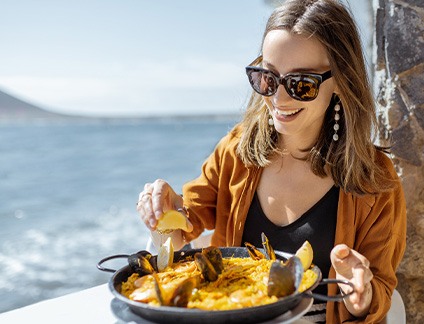 Smiling woman enjoying meal at restaurant on the water