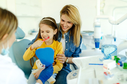 Child sitting on mom's lap while brushing teeth