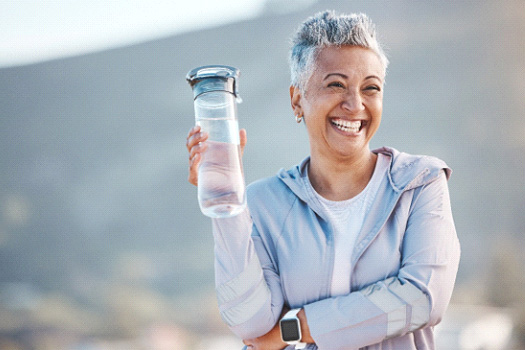 Woman smiling with water bottle on hike outside