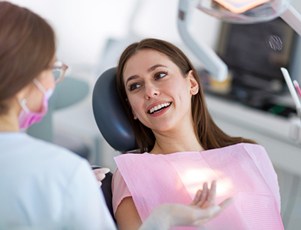 Dental patient leaning back in dental chair while talking to her dentist