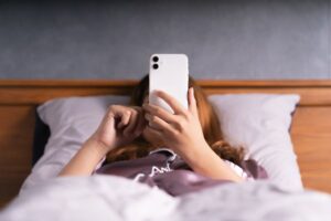 Woman looking at her phone while lying in bed