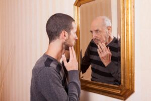 Man looking in mirror, imagining his older self