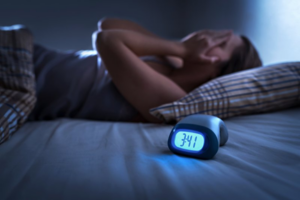 Woman can’t sleep while clock shows the time is 3:00 am