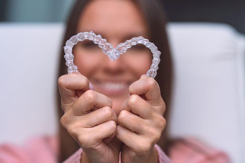 Woman holding Invisalign to camera in heart shape