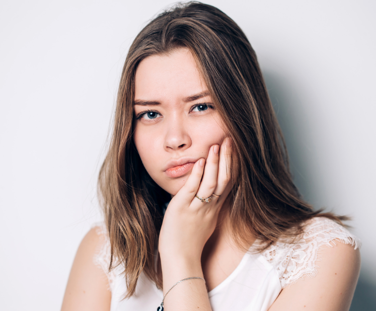 Girl holding face, looking uncomfortable or in pain