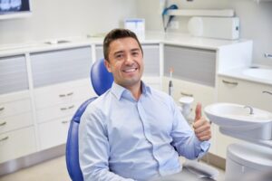 Man at the dentist smiling and holding a thumbs up